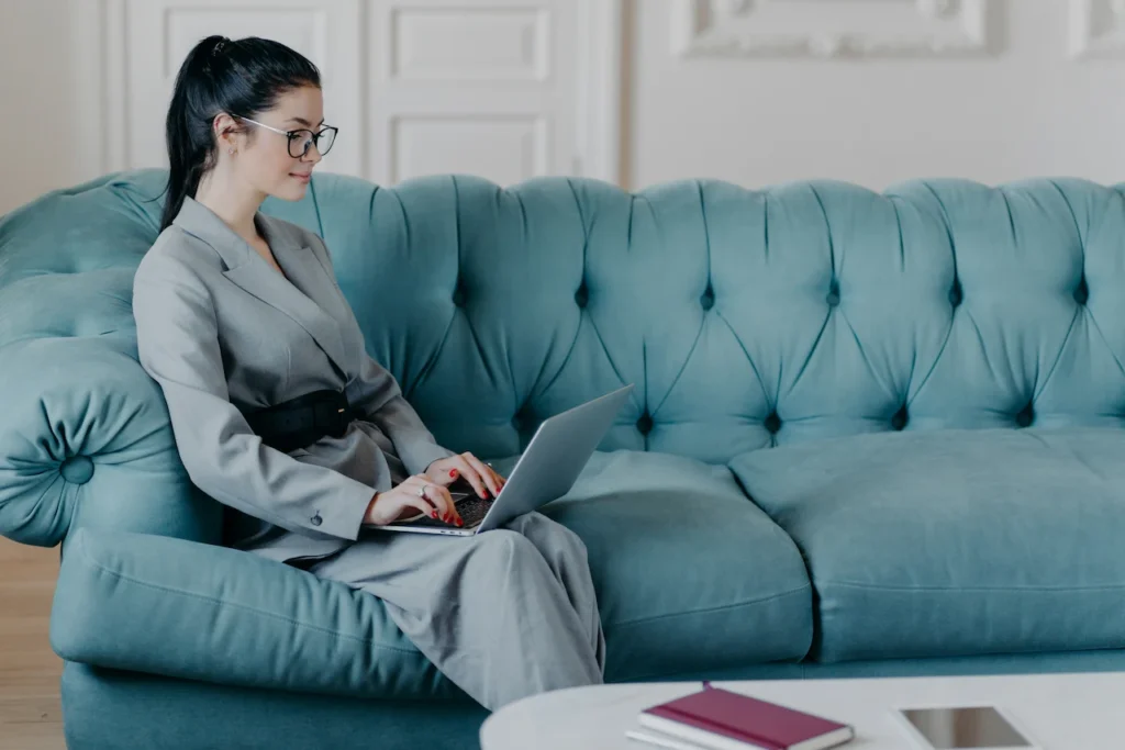 Woman working on laptop in lounge.